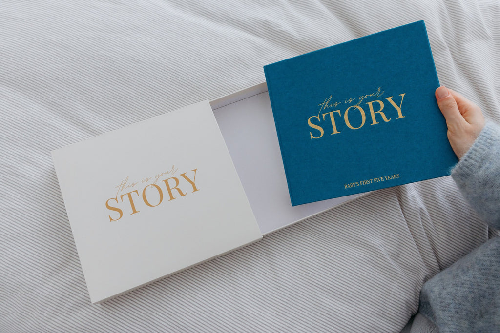 CheriBOO Baby Memory Book in Deep Sea Blue (deep petrol blue) sliding out of its keepsake box