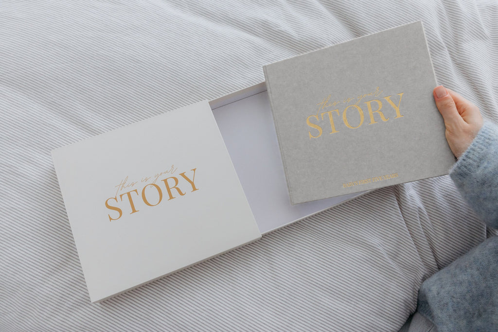CheriBOO Baby Memory Book First Edition in Light Gray sliding out of its keepsake box