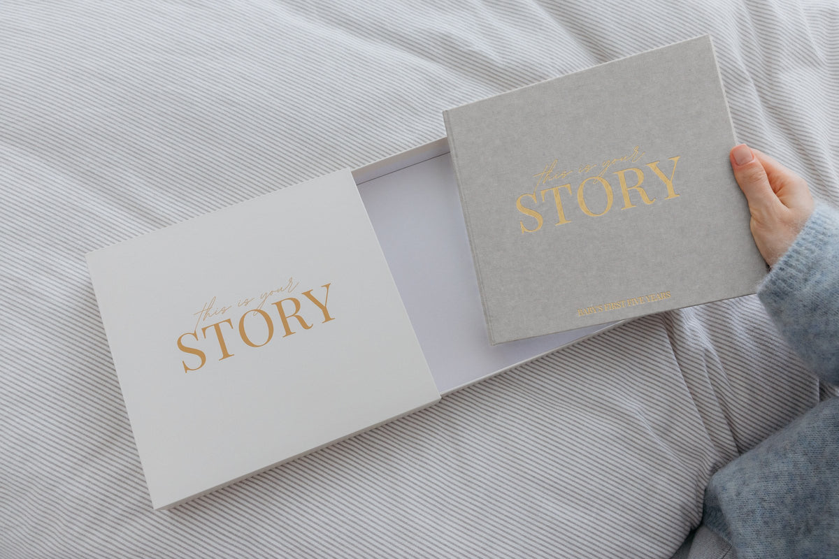 CheriBOO Baby Memory Book First Edition in Light Gray sliding out of its keepsake box