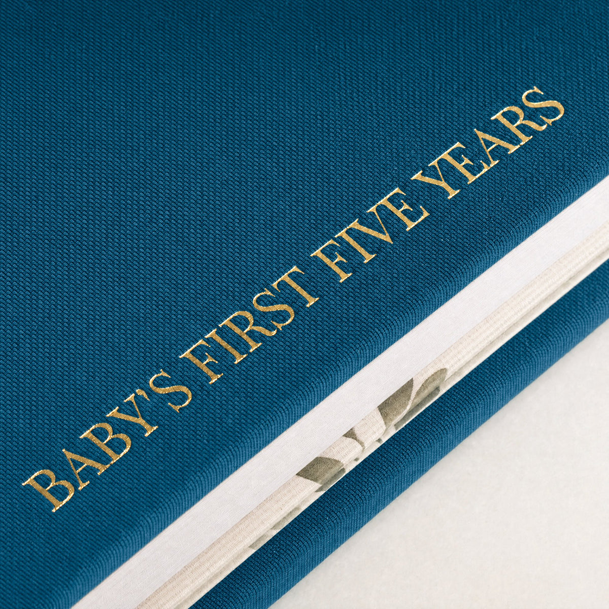 Close-up of the linen cover, the gold foil and the thick pages of the CheriBOO Baby Memory Book in Deep Sea Blue