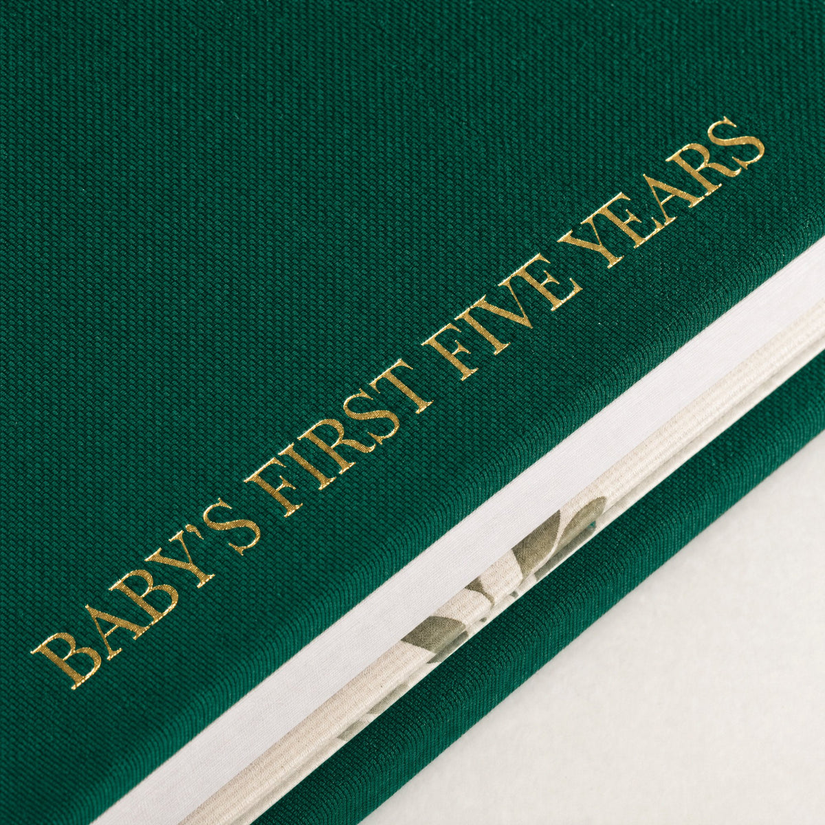 Close-up of the linen cover, the gold foil and the thick pages of the CheriBOO Baby Memory Book in Evergreen