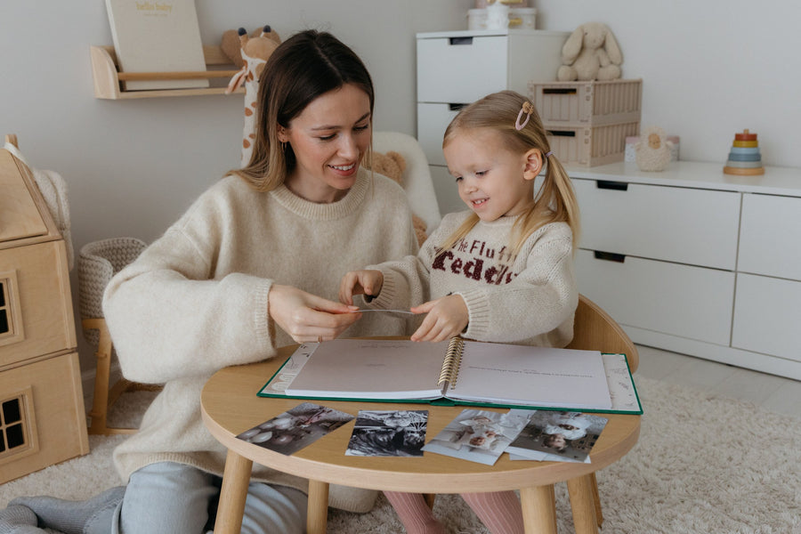 A mother and her daughter fill in the CheriBOO Baby Memory Book together at a small table