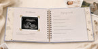 The CheriBOO Baby Memory Book in Lavender open on the ultrasound page, with printed photos beside it