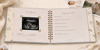 The CheriBOO Baby Memory Book First Edition in Light Gray open on the ultrasound page, with printed photos beside it